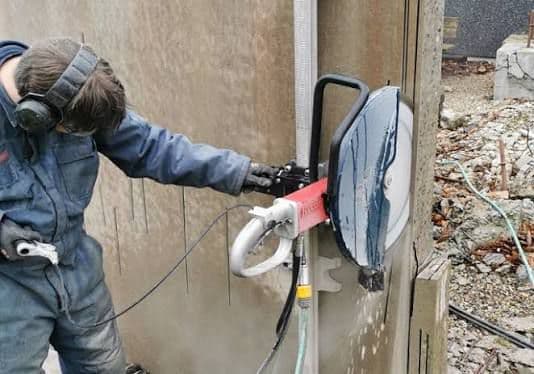 Construction worker cutting concrete wall for door opening — Kerala